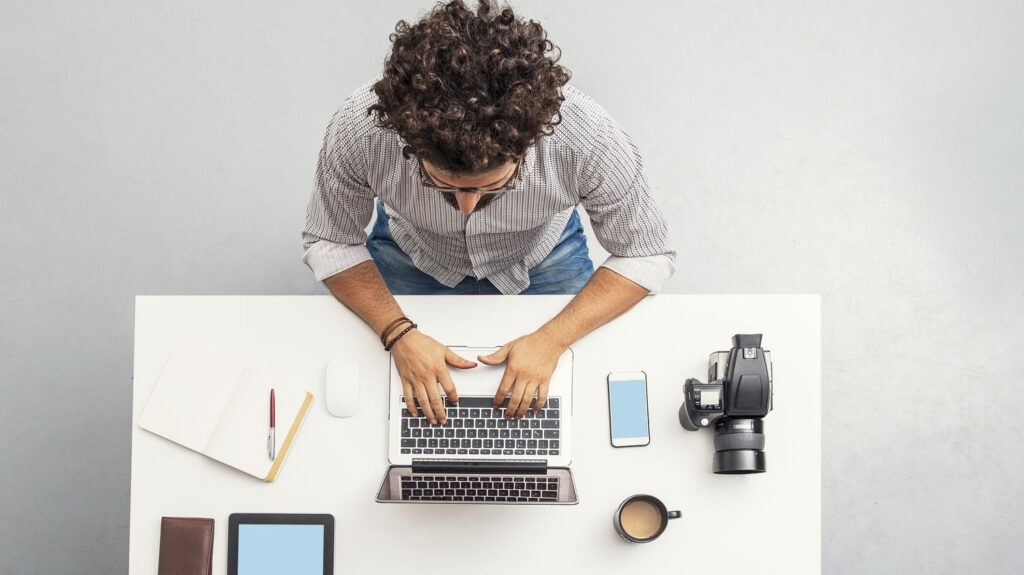 Homme sur un bureau avec un ordinateur ayant quitter l'école car il est autoentrepreneur sans diplôme et veut réussir