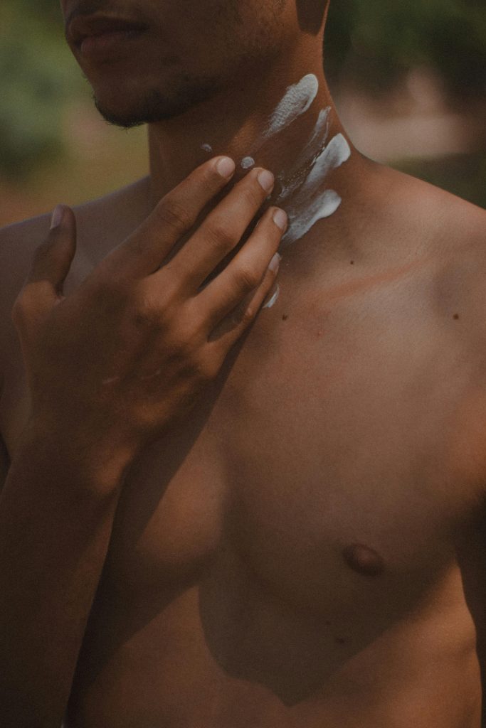 Close-up of a man applying lotion to his neck, highlighting skin care routine.