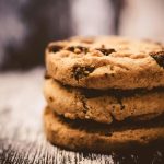 A macro shot of freshly baked stacked chocolate chip cookies creates a cozy dessert vibe.