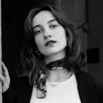 Stylish black and white portrait photograph of a woman with a neckerchief, embodying elegance and fashion.