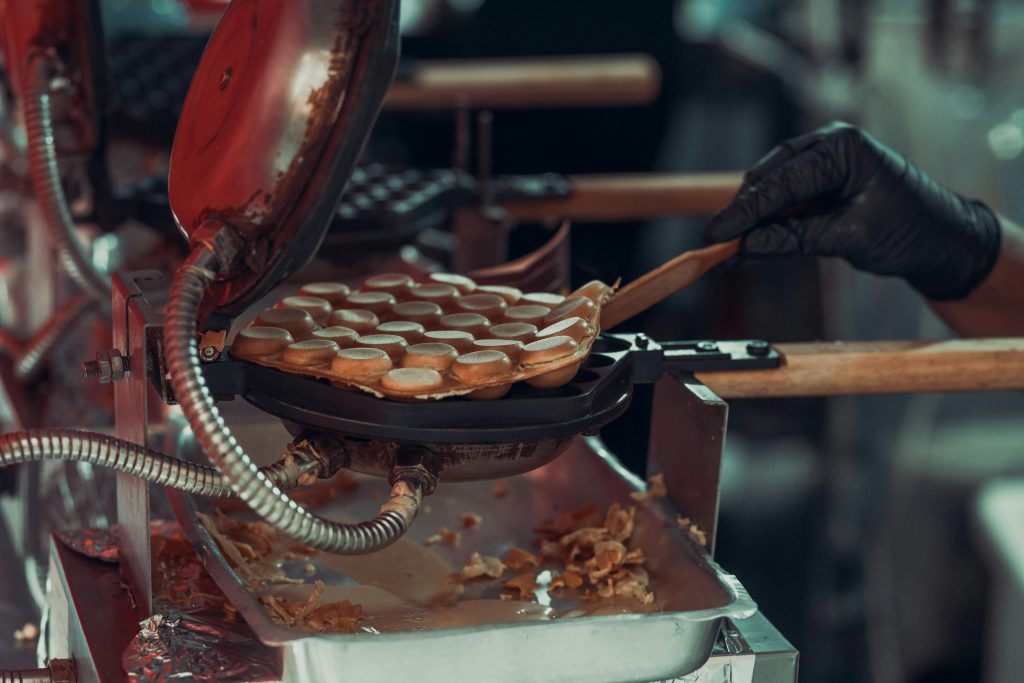 Close-up of bubble waffles cooking in a professional waffle maker at a street market.