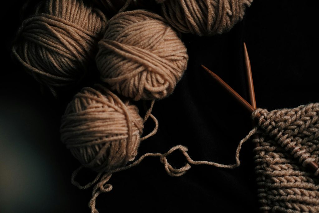 A close-up flat lay of brown yarn balls and knitting needles, showcasing a crafting hobby.