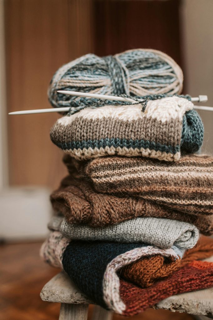 Cozy folded knitted scarves with yarn and needles, perfect for winter crafts.
